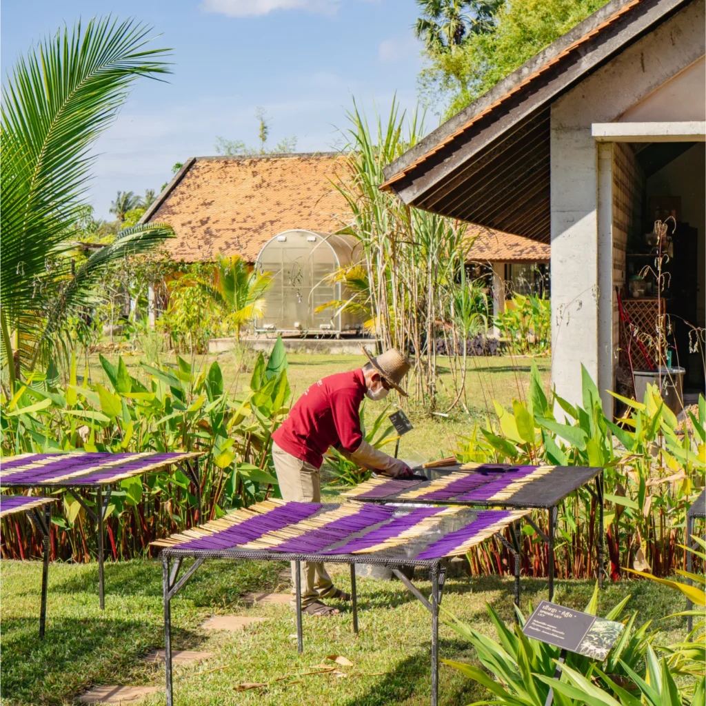 Artisan spreading incense sticks on a table tray for drying.