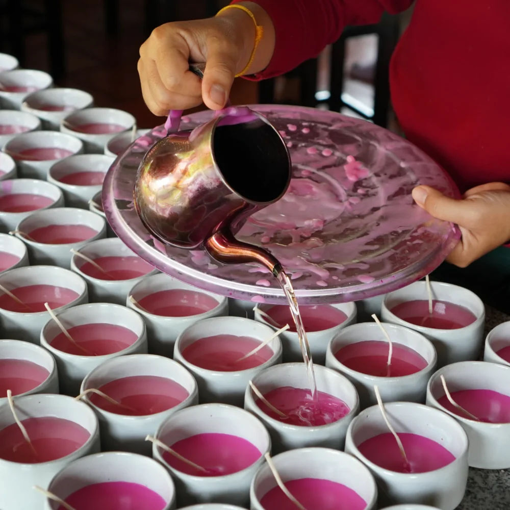 Candle in ceramic, making process, artisan is pouring the lotus mixture inside the ceramic recipient.