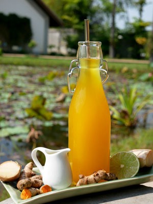 Home made curcuma juice in a glass bottle with a stainless steel straw