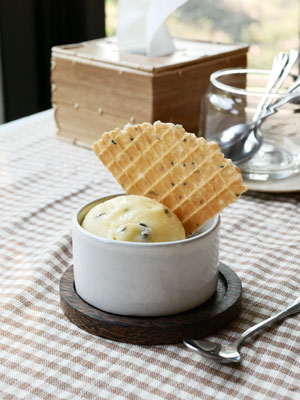 Home made passion ice cream in a white ceramic cup with a home made crispy cone piece