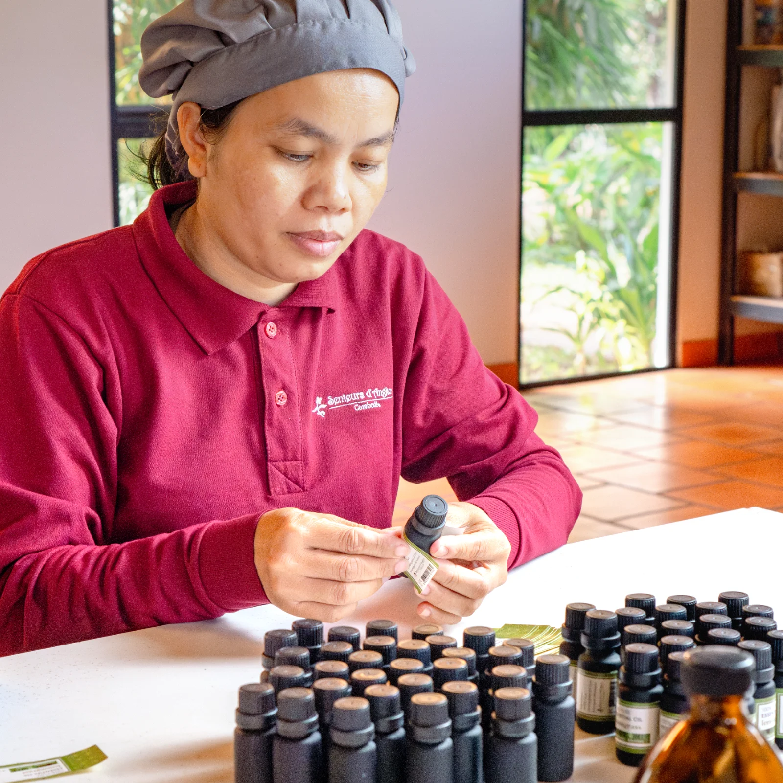 Artisan applying sticker on lemongrass essential oil bottle
