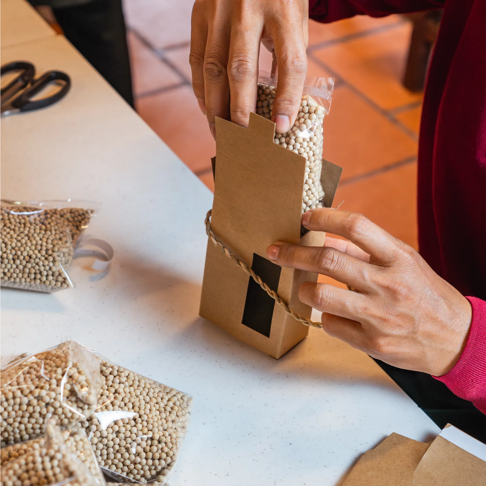 woman packing white Kampot pepper into kraft box.