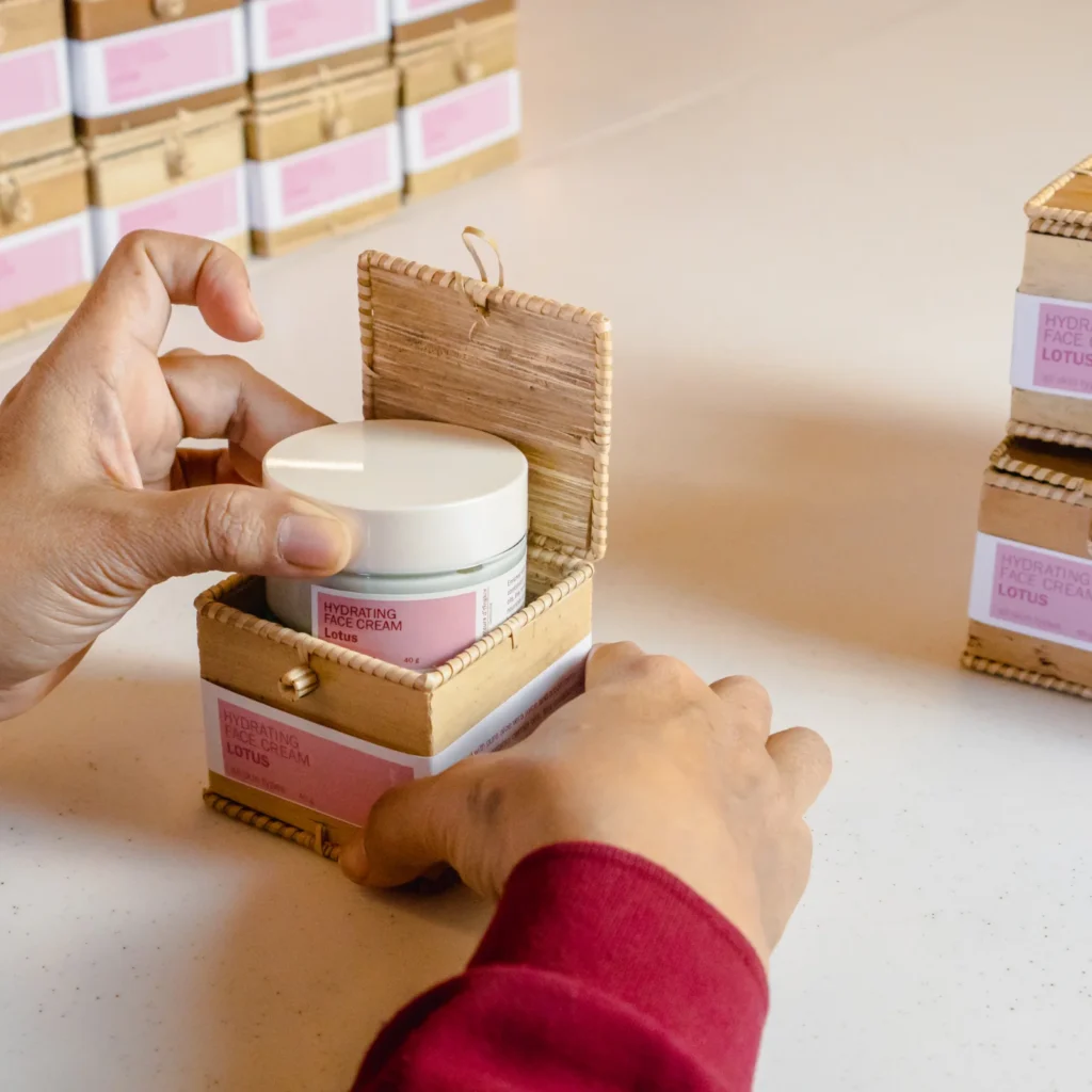 Artisan packing a facial skin care container inside a Krebei Riel box.