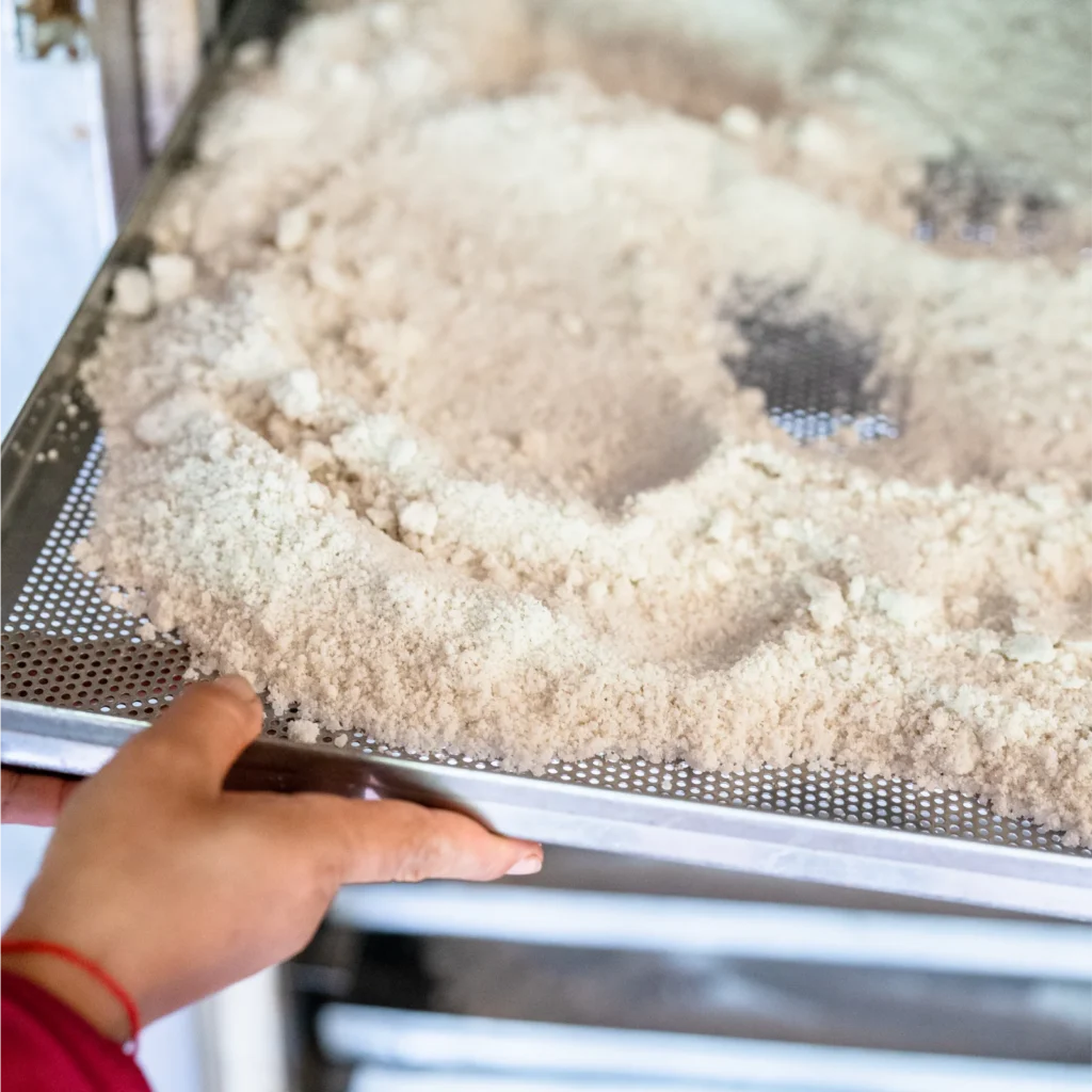 Close up on Kampot salt in a drying tray pulled by artisan