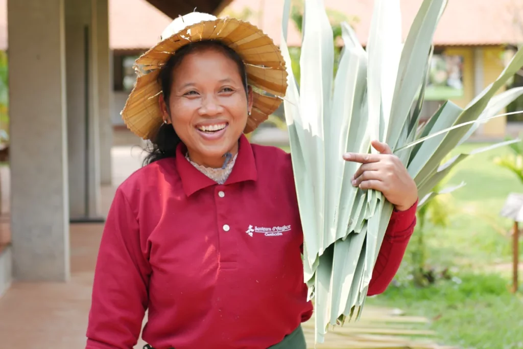 Artisan walking and smiling while carrying a piece of sugar palm leaf to create natural packaging.