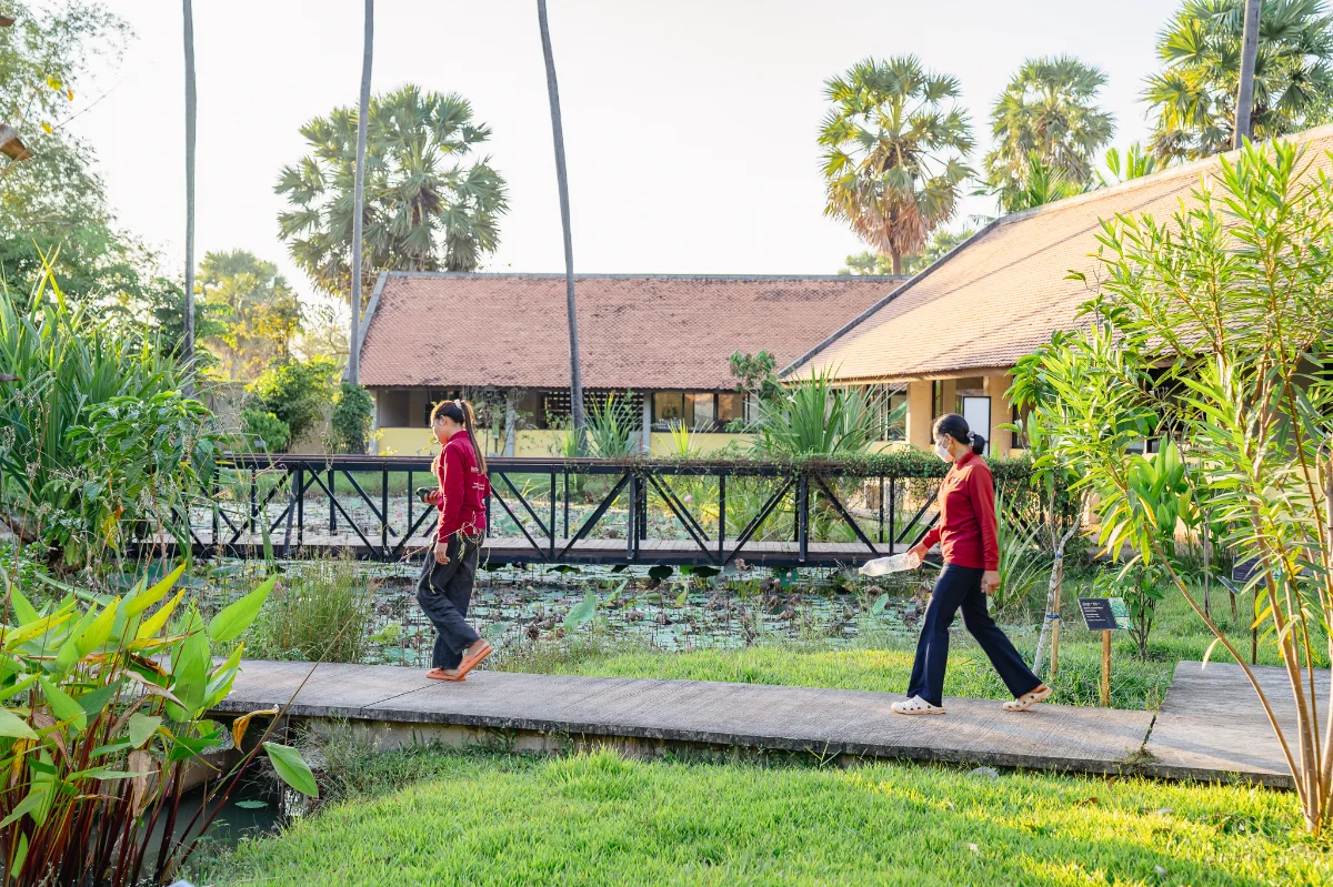 22 women staff are walking through the workshop tropical garden.